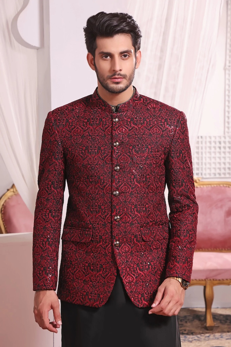 May include: A red patterned blazer with a mandarin collar and button closure. The blazer features a black and red paisley design and is embellished with sequins.