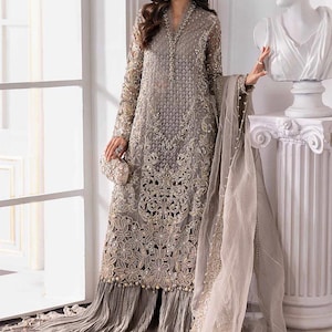 May include: A long, gray embroidered formal dress with intricate floral patterns and bead embellishments. The dress features long sleeves, a flowing skirt, and a matching sheer scarf. A small, embellished clutch is held at the waist.