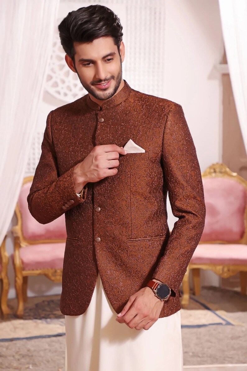 May include: A brown patterned blazer with a mandarin collar and a white pocket square. The blazer has a button closure and a single button on each cuff.
