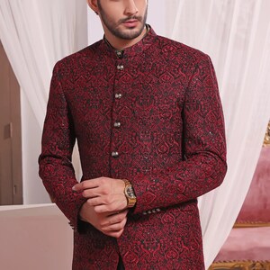 May include: A maroon blazer with a black and gold patterned design. The blazer has a mandarin collar and a button closure.