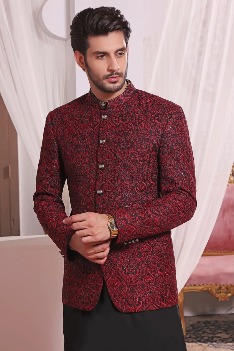 May include: A maroon blazer with a black and gold patterned design. The blazer has a mandarin collar and a button closure.