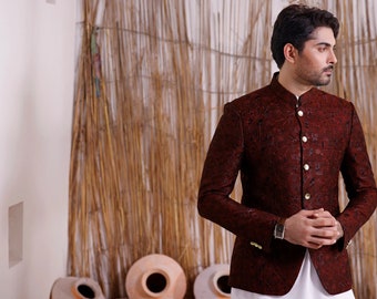 May include: A maroon patterned blazer with a mandarin collar and gold buttons. The blazer is worn over a white shirt.