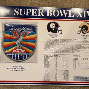 May include: A commemorative patch for Super Bowl XIV, featuring the Super Bowl logo and the words "Super Bowl XIV" and "Rose Bowl". The patch is surrounded by a blue, red, and yellow striped border. The patch is on a white background with the text "Pittsburgh Steelers 31" and "Los Angeles Rams 19" below the patch. The text "Rose Bowl, Pasadena, California, January 20, 1980" is below the text.