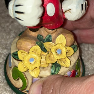 Pu&ograve; includere: Una statuetta in ceramica dipinta a mano di Topolino con pantaloncini rossi e guanti bianchi. &Egrave; in piedi su una base decorata con fiori gialli e foglie verdi.