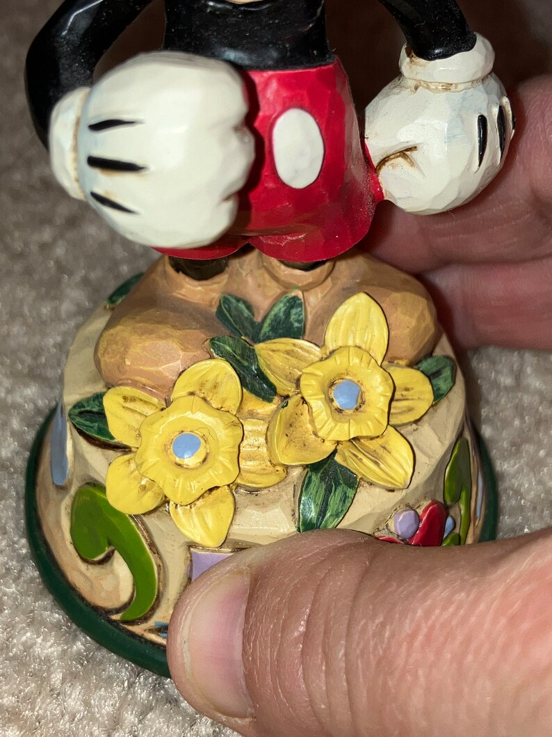 Pu&ograve; includere: Una statuetta in ceramica dipinta a mano di Topolino con pantaloncini rossi e guanti bianchi. &Egrave; in piedi su una base decorata con fiori gialli e foglie verdi.