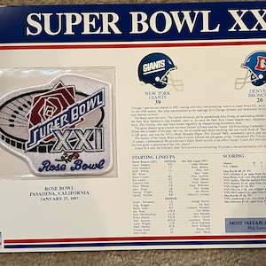 May include: A white patch with a red rose and the text "Super Bowl XXI Rose Bowl" on it. The patch is surrounded by a white border with a black outline. The patch is on a white background with a blue and red border. The text "Super Bowl XXI" is in black and the text "Rose Bowl" is in red. The patch is a collectible item for fans of the New York Giants and the Denver Broncos.