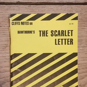 May include: A yellow and black striped Cliffs Notes book cover with the title "The Scarlet Letter" by Nathaniel Hawthorne. The cover also features the Cliffs Notes logo and the tagline "Your Key to the Classics".