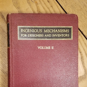 May include: A burgundy leather-bound book titled "Ingenious Mechanisms for Designers and Inventors, Volume II".