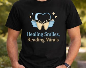 May include: Black t-shirt with a dental-themed graphic. The design features a tooth and an open book, with the text "Healing Smiles, Reading Minds" in blue and tan. The shirt is short-sleeved.