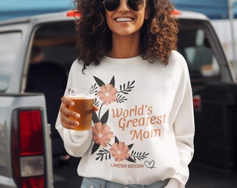 May include: A white long-sleeve sweatshirt featuring a graphic of pink flowers and green leaves with the text "World's Greatest Mom" and "LIMITED EDITION" printed in brown, accompanied by a small heart outline.