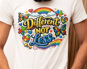 May include: A white short-sleeved t-shirt featuring a colorful graphic with the text Different NOT Less. The design includes a rainbow, butterflies, puzzle pieces, and hearts in vibrant primary colors, creating a bold and detailed illustration.