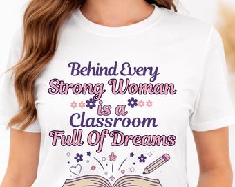 May include: White t-shirt with the text "Behind Every Strong Woman is a Classroom Full Of Dreams" in purple and pink. The design includes flowers, a heart, and an open book with a pencil.