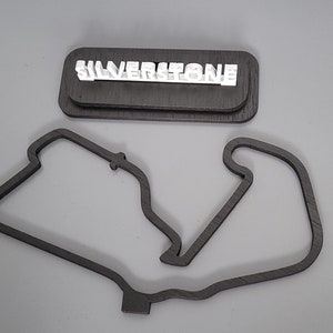 May include: A wooden model of the Silverstone racetrack with the name "SILVERSTONE" in white letters on a separate wooden base.
