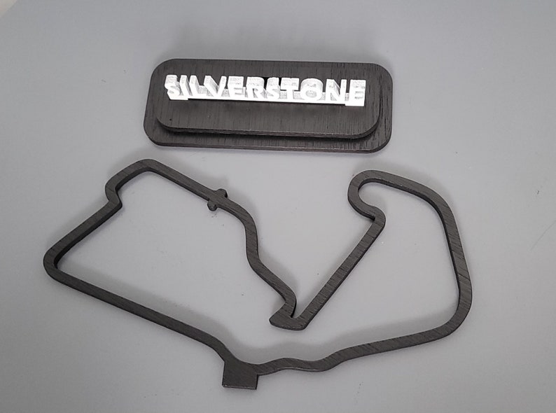 May include: A wooden model of the Silverstone racetrack with the name "SILVERSTONE" in white letters on a separate wooden base.