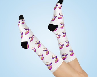 Puede incluir: Calcetines blancos con un patrón repetido de formas abstractas moradas y doradas. Los calcetines tienen talones y dedos negros. Fondo azul claro.