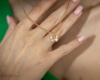 May include: A gold chain necklace with a delicate butterfly pendant. The butterfly is made of gold and has a textured surface.