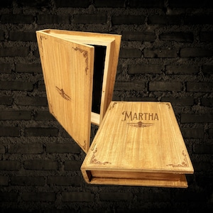 May include: A wooden box with a hinged lid, the lid is open revealing a black interior. The box is decorated with a floral design and the name "MARTHA" is engraved on the front.