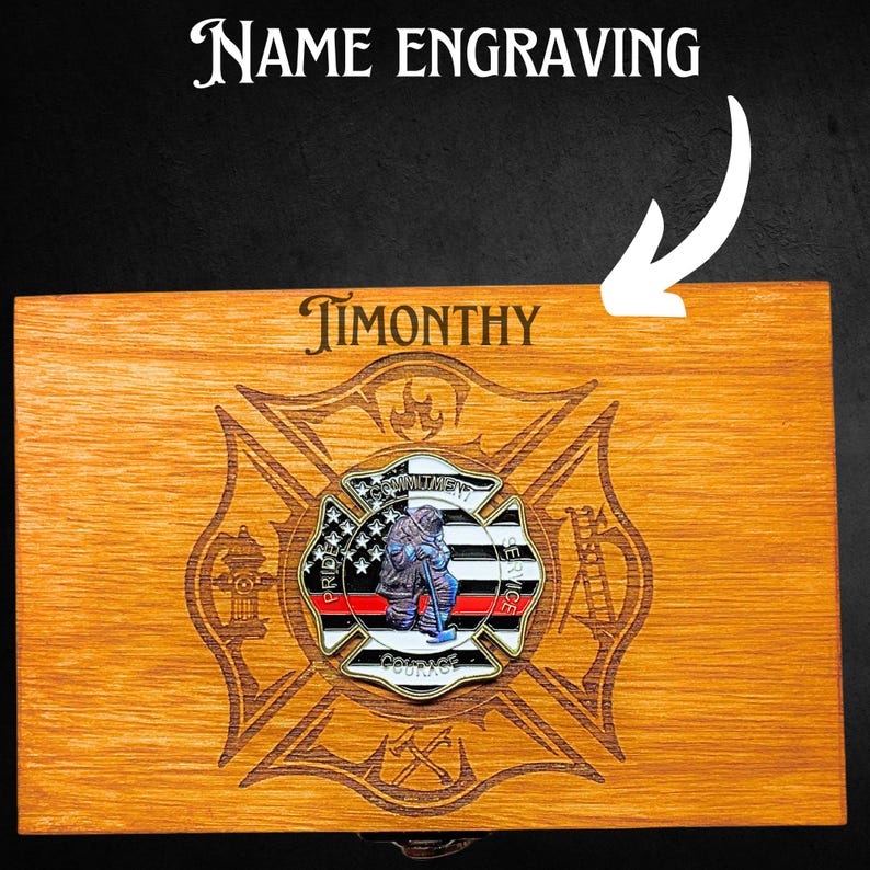 K&ouml;nnte beinhalten: Eine Holzkiste mit einem eingravierten Feuerwehr-Emblem auf dem Deckel. Das Emblem zeigt einen Feuerwehrmann mit Helm und einer roten Linie in der Mitte. Die Worte "Stolz", "Mut", "Engagement" und "Dienst" sind um das Emblem herum eingraviert. Die Box ist mit dem Namen "TIMONTHY" auf der Oberseite personalisiert.