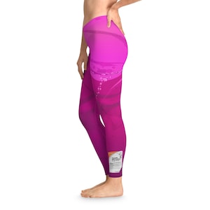 Può includere: Leggings rosa con un design sfumato che presenta un motivo a spirale e una piccola etichetta sulla parte inferiore della gamba. L'etichetta ha il testo "Lubrificante personale spray monouso".