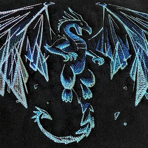 May include: A blue and white embroidered dragon with wings spread wide. The dragon is on a black background.