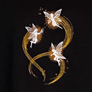 May include: Three white fairies with wings fly in a circle on a black background. The fairies are surrounded by a golden trail.