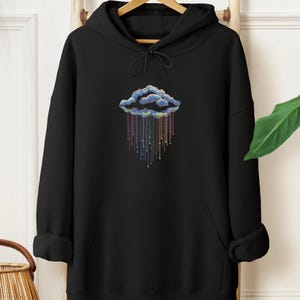 May include: Black hoodie featuring a colourful cloud design. The cloud is outlined in blue with rainbow-coloured rain. The hoodie has a drawstring hood and a front pocket.