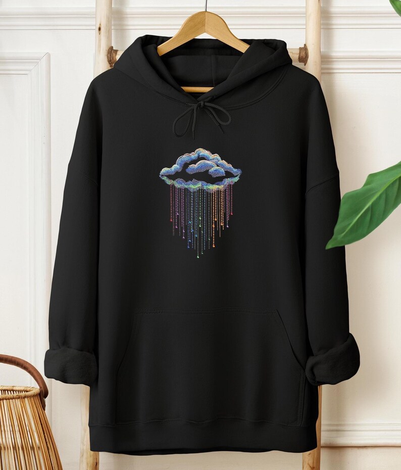 May include: Black hoodie featuring a colourful cloud design. The cloud is outlined in blue with rainbow-coloured rain. The hoodie has a drawstring hood and a front pocket.