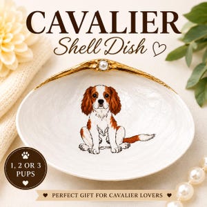 May include: White shell dish with a gold rim and a pearl accent. The dish features a Cavalier King Charles Spaniel illustration. Text on the dish reads "CAVALIER Shell Dish" and "1, 2 OR 3 PUPS".