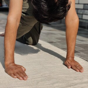 K&ouml;nnte beinhalten: Eine Person macht eine Yoga-Pose auf einer wei&szlig;en Yogamatte. Die Person tr&auml;gt ein wei&szlig;es Hemd und eine Khakihose.