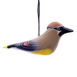 May include: A wooden bird ornament painted to resemble a Cedar Waxwing. The bird is brown with black wings and a yellow belly. It has a red patch on its wing and a black head with a white eye.