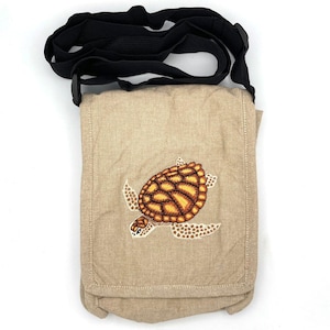 May include: A beige canvas crossbody bag with an embroidered sea turtle design. The turtle is brown and yellow with a white shell.