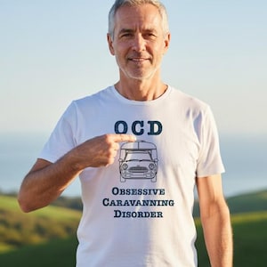 May include: A white short-sleeved t-shirt featuring a dark blue graphic of a car towing a caravan. Above the graphic is the text OCD, and below the graphic is the text OBSESSIVE CARAVANNING DISORDER in a bold, distressed, serif font style.