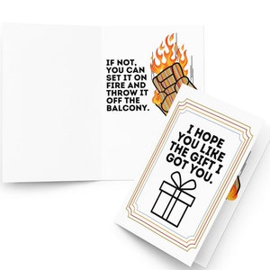 May include: A greeting card with a humorous message about a gift. The card features a cartoon fist on fire and the text "IF NOT, YOU CAN SET IT ON FIRE AND THROW IT OFF THE BALCONY." The inside of the card has a black and white illustration of a gift box and the text "I HOPE YOU LIKE THE GIFT I GOT YOU."