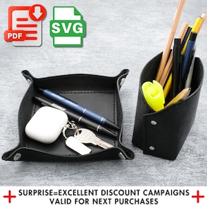 May include: Two black leather desk organizers, one a tray with a key chain and two pens, the other a pencil holder with a variety of pencils and pens. The text "SURPRISE=EXCELLENT DISCOUNT CAMPAIGNS VALID FOR NEXT PURCHASES" is at the bottom of the image.
