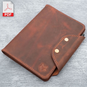 May include: A brown leather notebook cover with a pen holder and two brass snaps. The cover has a subtle distressed look and a small fox logo on the front.