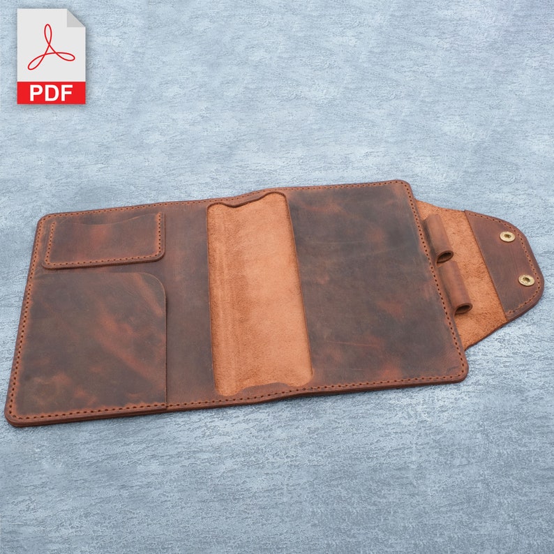 May include: A brown leather notebook cover with a flap and a pocket on the front. The cover is open to reveal a brown leather interior with a pen holder and a slot for a notebook.