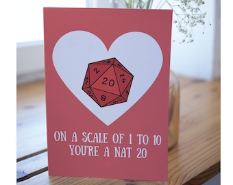 Op de afbeelding: Een rode en witte kaart met een hartvorm en een rode twintigzijdige dobbelsteen erin. De tekst op de kaart luidt "Op een schaal van 1 tot 10 ben je een Nat 20".