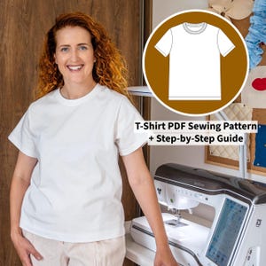Op de afbeelding: Een vrouw draagt een wit t-shirt naast een naaimachine. Een cirkelvormige afbeelding toont een t-shirtontwerp met de tekst "T-Shirt PDF Sewing Pattern + Step-by-Step Guide". De achtergrond omvat een houten deur en een prikbord.