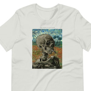 Może przedstawiać: Biały T-shirt z nadrukiem szkieletu palącego papierosa na polu kwiatów. Tekst "Van Gogh x Van Gogh" jest nadrukowany nad obrazem.