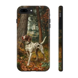 Może przedstawiać: Etui na telefon z obrazem psa w lesie. Pies jest biały z brązowymi plamami i brązową głową, stojący wśród opadłych liści. Tło lasu obejmuje wysokie drzewa i jesienne liście.