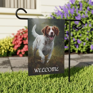 Könnte beinhalten: Eine Willkommens-Gartenflagge mit einem weißen und braunen Hund auf schwarzem Hintergrund. Der Hund rennt mit herausgestreckter Zunge auf den Betrachter zu. Der Text "WELCOME" ist unten auf der Flagge in Weiß gedruckt.