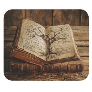 May include: An open antique book with a tree drawn on the pages. The book is resting on a stack of other books on a wooden surface.