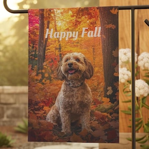 May include: A rectangular garden flag featuring a light brown, curly-haired dog sitting in a forest filled with vibrant orange, red, and yellow autumn leaves. The text Happy Fall is printed in white, sans-serif letters at the top of the flag.