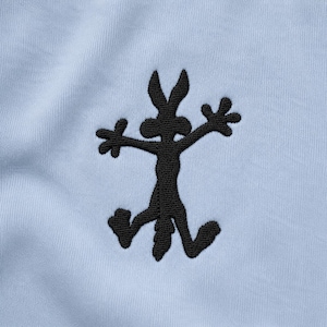 May include: A light blue fabric featuring a black embroidered graphic of a stylized, flattened cartoon coyote character with outstretched limbs, a pointed tail, and large ears, centered on the smooth, woven textile surface.