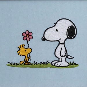 Könnte beinhalten: Gesticktes Bild von Snoopy und Woodstock. Snoopy, ein weißer Hund mit schwarzen Ohren, steht Woodstock gegenüber, einem gelben Vogel, der eine rosa Blume hält. Sie stehen auf grünem Gras vor einem hellblauen Hintergrund.
