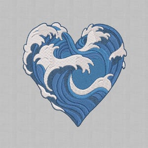May include: Embroidered heart-shaped design featuring a stylized ocean wave pattern in shades of blue and white. The heart is filled with swirling waves, creating a dynamic and visually appealing image. The design is set against a light gray background.