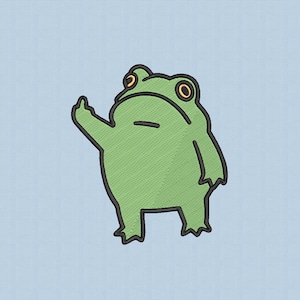 May include: A green frog cartoon with black outlines and orange eyes, giving the middle finger. The frog is embroidered on a light blue background. The frog is standing and has a grumpy expression.