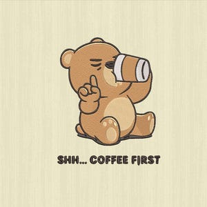Puede incluir: Diseño bordado de un oso pardo bebiendo de una taza de café, con el dedo índice levantado. El texto "SHH... COFFEE FIRST" está debajo del oso. El oso está sentado sobre un fondo beige claro.