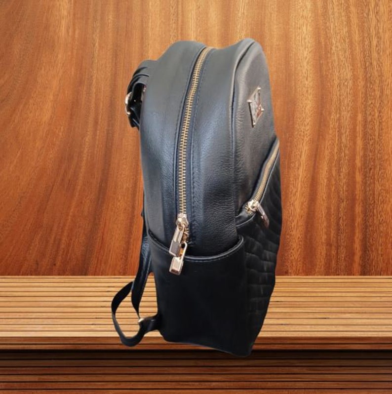 May include: A black leather backpack with a quilted design and gold accents. The backpack has a zipper closure and a top handle.