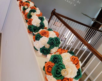 Bruidsmeisjes 20 cm brocheboeketten met verbrande oranje, jagersgroene en crèmekleurige bloemen. Gouden broches en gouden bling handvat